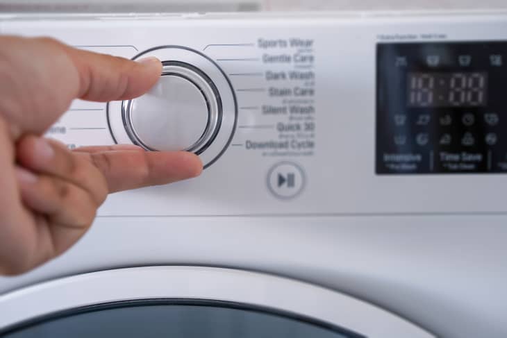 Cropped Hand Of Person Adjusting Washing Machine Knob