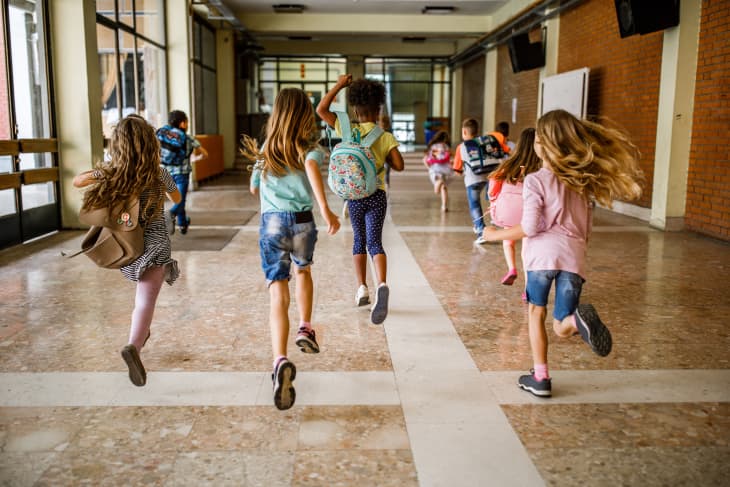Back view of elementary students running in the school hallway.