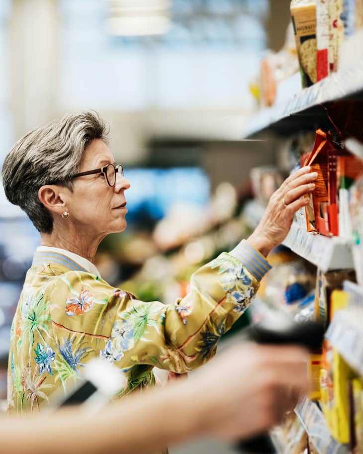 Senior Woman Picking Goods From Shelf At Supermarket