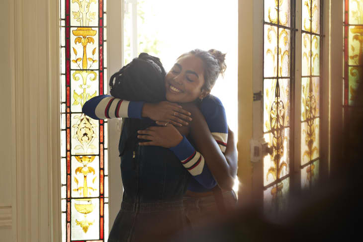Young female friends embracing each other while standing at home entrance