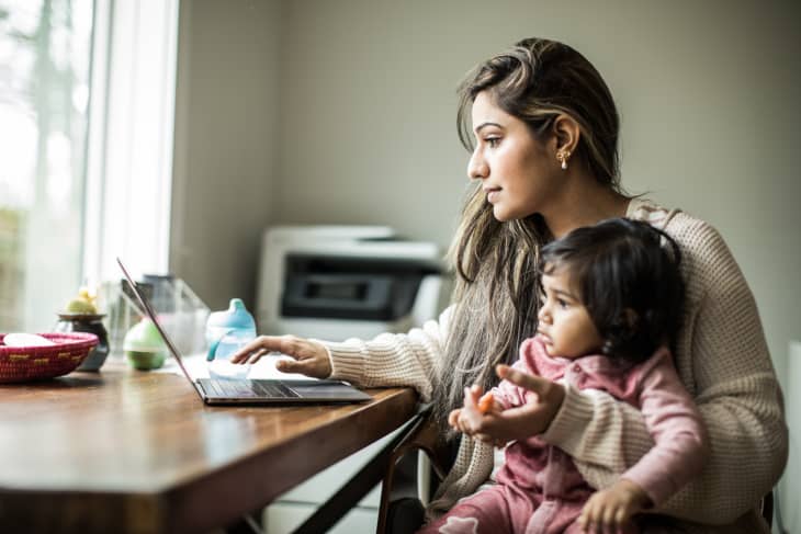 Mother multi-tasking with infant daughter in home office