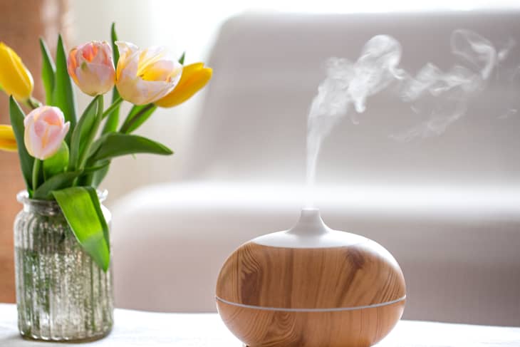 Aroma oil diffuser lamp on the table on a blurred background with a beautiful spring bouquet of tulips.