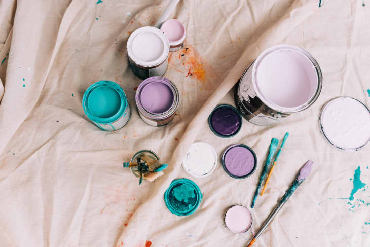 Cans of colorful paint from a high up angle on a drop cloth.
