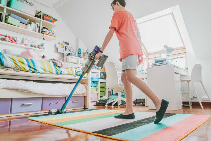 Low section male teenager with vacuum cleaner bedroom