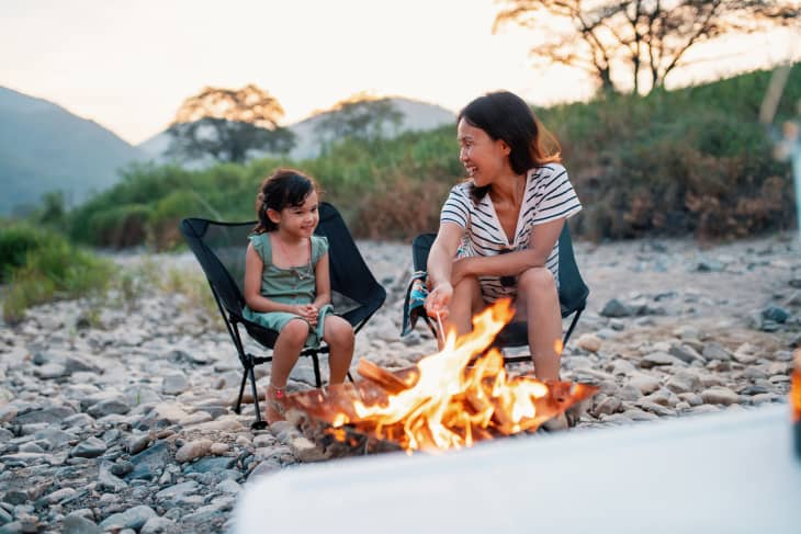 Young girl roasting marshmallows with her mother on a campfire.