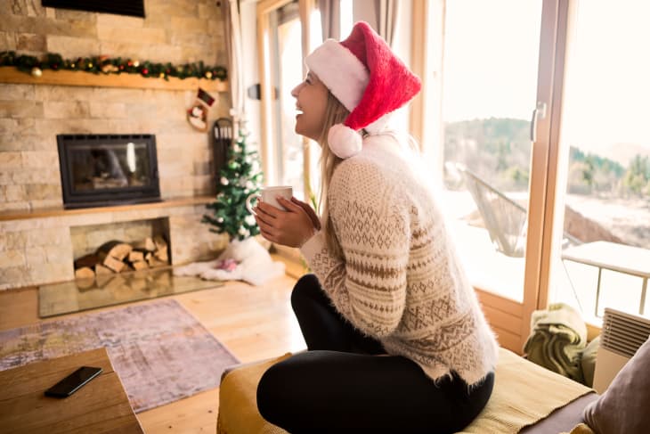 Young woman drinking tea on Christmas morning sitting on sofa