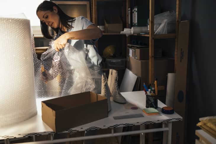 Young businesswoman cutting a piece of bubble wrap to secure the goods that she will ship to her customer