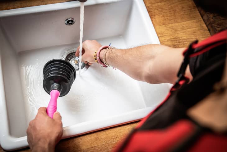 Plumber repairs kitchen sinks with plungers