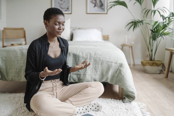 Relaxed woman sitting on the floor practicing meditation after reading book