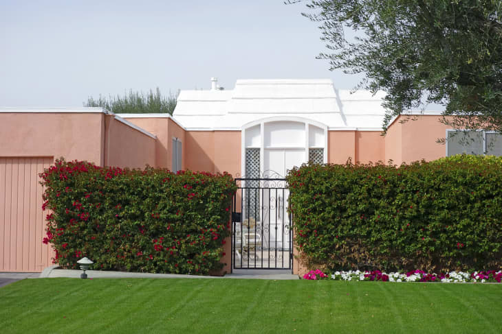 粉红色和白色的门和墙中世纪风格的联排别墅。带草坪的牵牛花和三角梅花园。