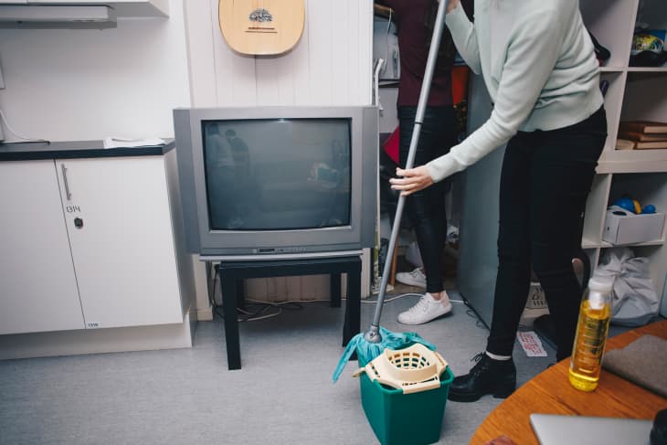Low section of woman holding mop in bucket at college dorm