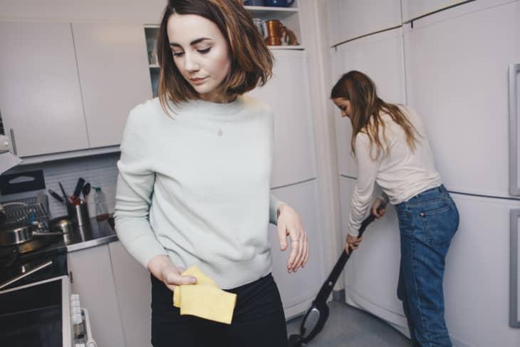 Female roommates cleaning kitchen in college dorm