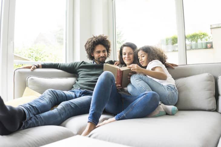 Happy family sitting on couch, reading book