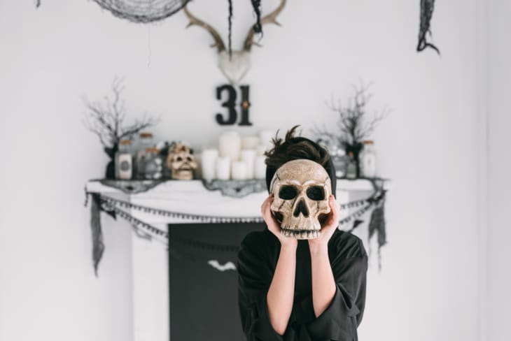 A young boy holding a skull in front of his face at a halloween party