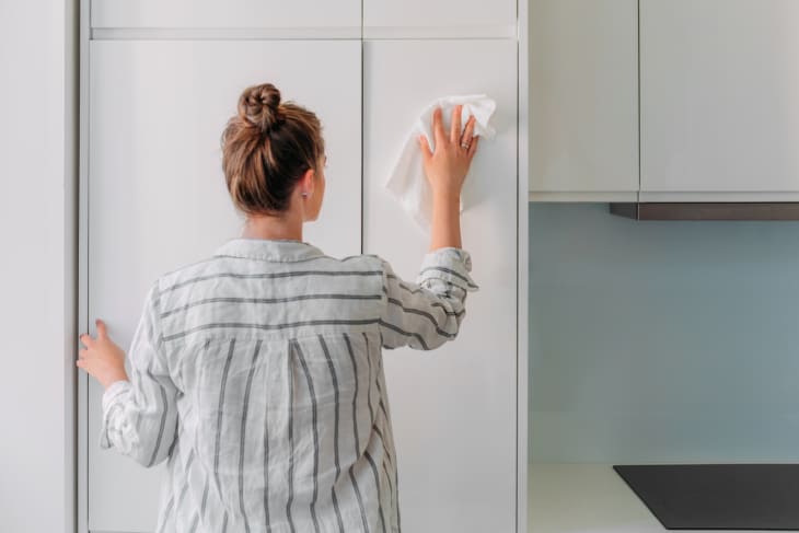 woman cleaning cabinets with disinfectant wipe