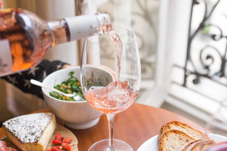 Pouring rosé into a wine glass with cheese platter