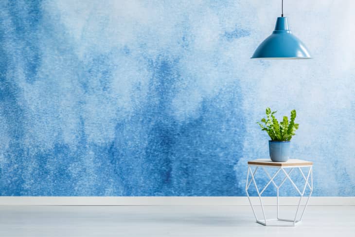 Blue lamp above modern table with plant in empty room interior with copy space on ombre wall