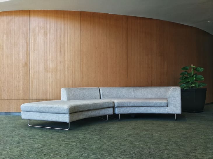 long curved lounge sofa couch against wood paneled wall