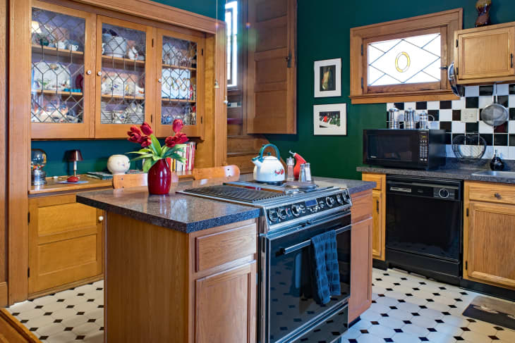 Dayton, Ohio, USA  2018: Green kitchen with built-in china cabinet, center island, black &amp; white themed decor &amp; back stairway in an hundred-year-old house.