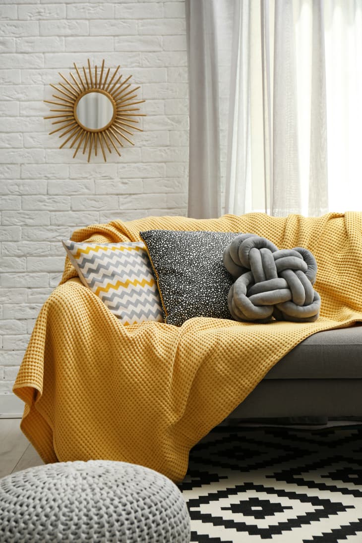 Pillows and a yellow blanket on a gray sofa in living room