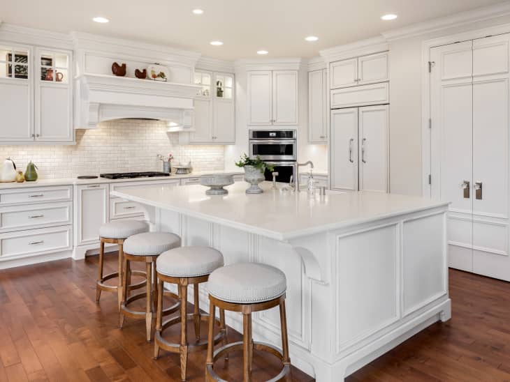 Beautiful kitchen in new traditional style luxury home. Features white island, counters, and cabinetry, and dark hardwood floors