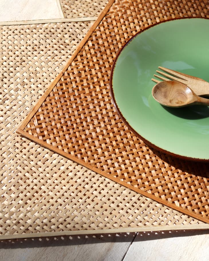 rattan placemats in a couple different colors. A green plate with a natural beige colored spoon and fork on top