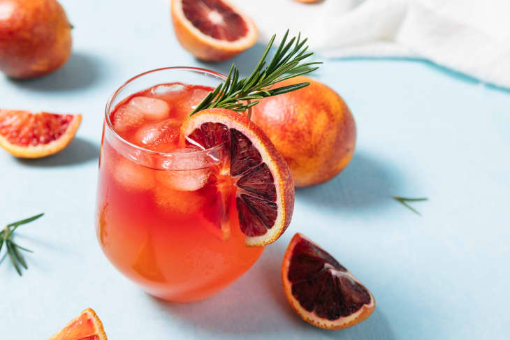 Delicious Blood Orange Bourbon Smash Cocktail on light blue background. Summer cocktails, refreshing drinks, low alcohol mocktail concept