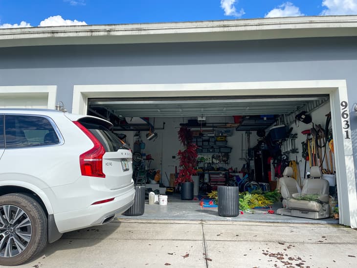 An unorganized garage filled with a lot of stuff in a neighborhood.