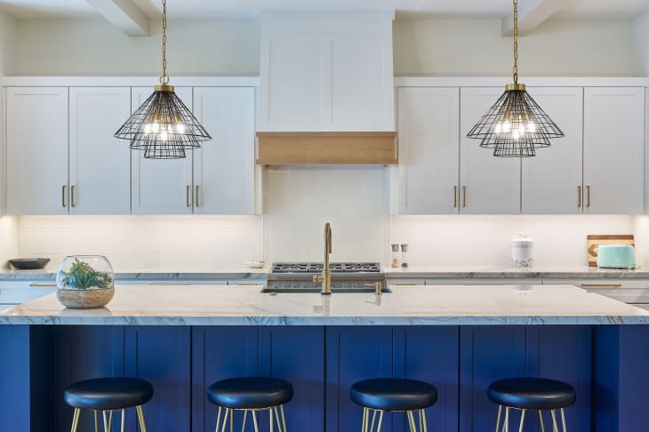 Straight on view of contemporary kitchen with quartzite countertops and blue kitchen island