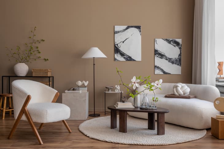 living room interior with mock up poster frame, boucle sofa, wooden coffee table, round carpet, white armchair, magnolia and personal accessories