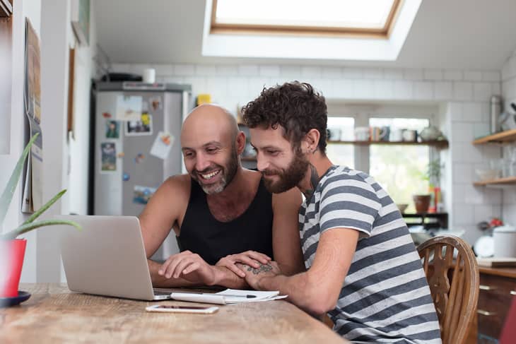 Gay couple using laptop in the kitchen