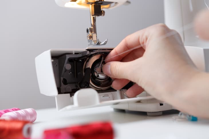 Hand inserts bobbin in sewing-machine