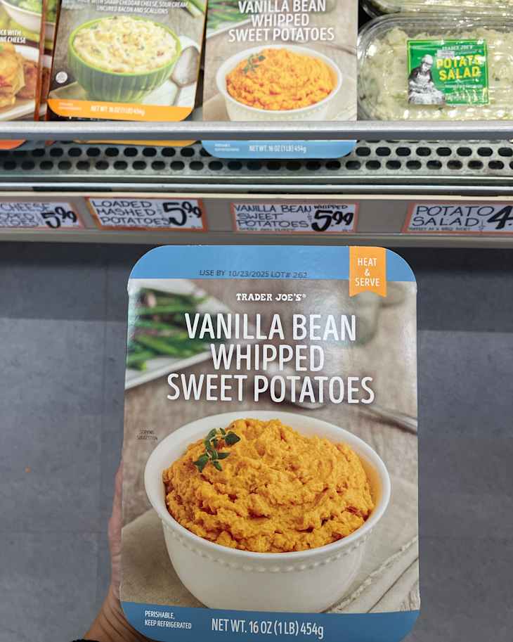 Container of Trader Joe's Vanilla Bean Whipped Sweet Potatoes with a serving suggestion in a white bowl, displayed in a grocery aisle.