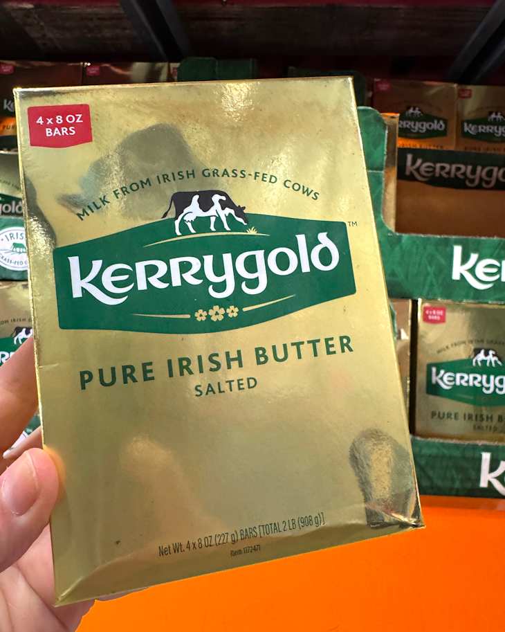 Gold packaging of Kerrygold Pure Irish Butter, featuring a hand holding the box, with other boxes in the background.