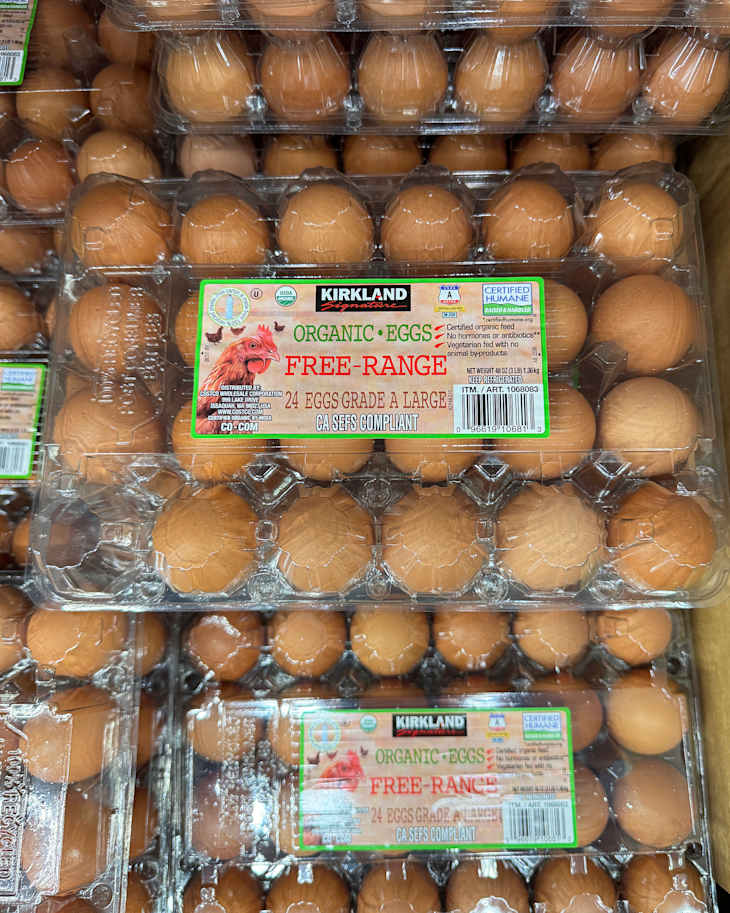 Cartons of organic free-range eggs stacked in a grocery store, featuring labels with product details.