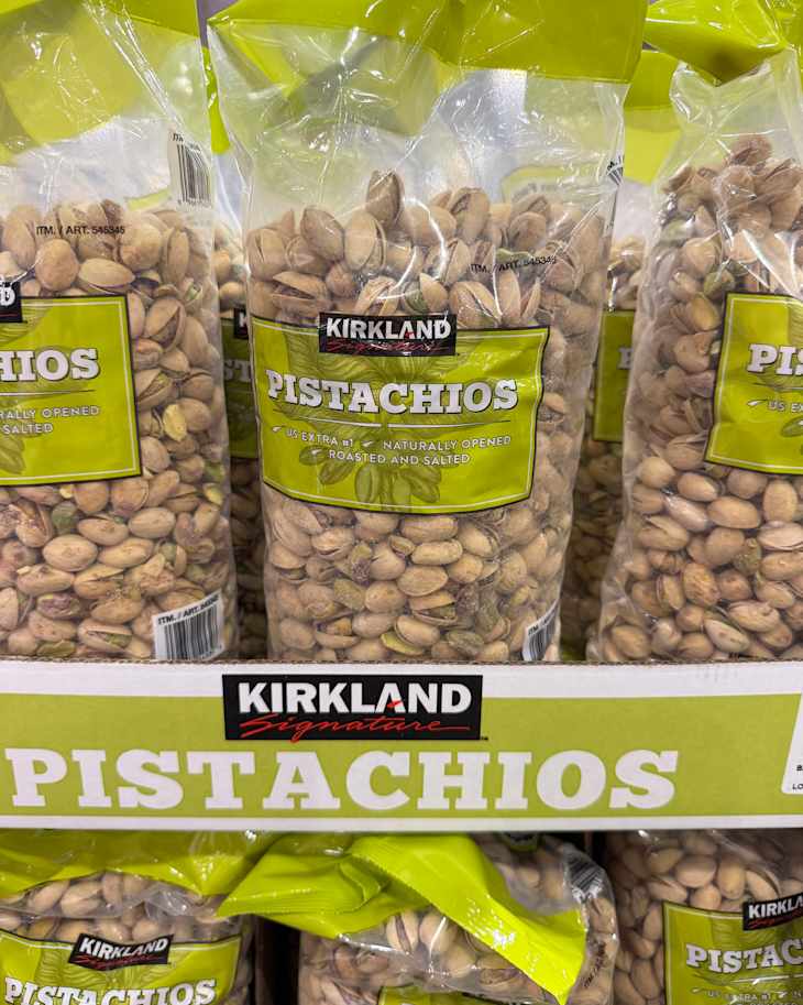 Bags of Kirkland pistachios, labeled as roasted and salted, displayed on a store shelf.