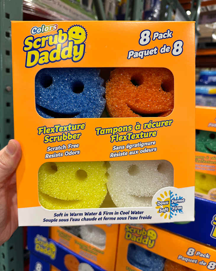 Colorful Scrub Daddy sponges in a box, featuring blue, orange, yellow, and white sponges with smiley faces.