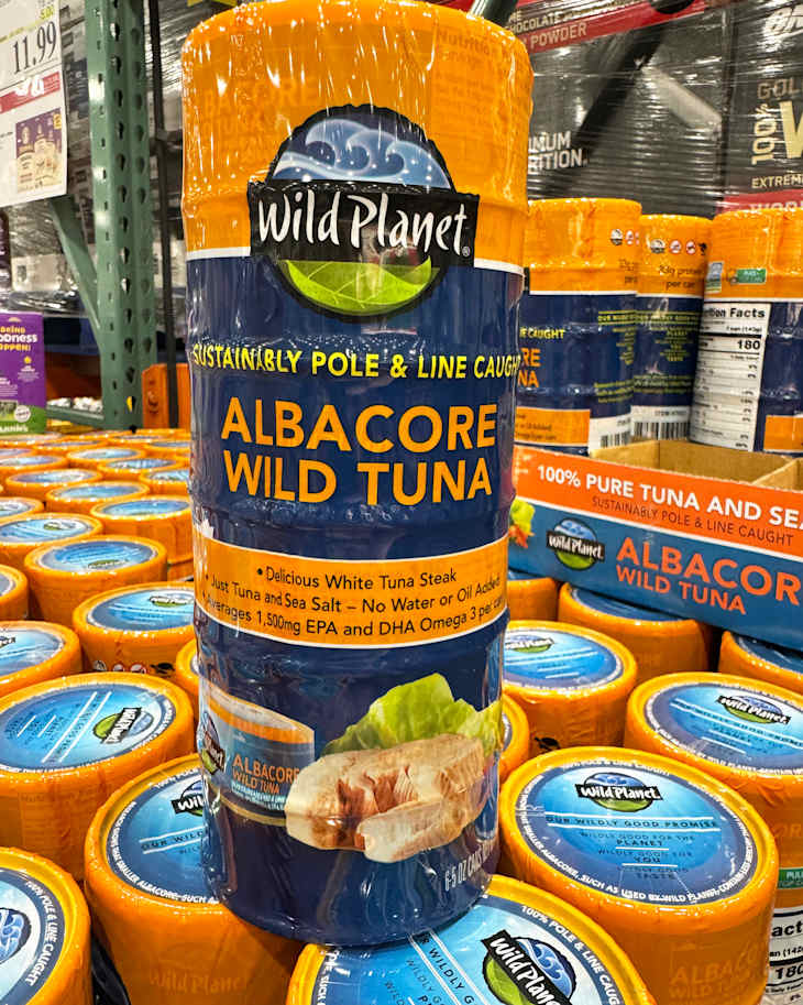 Canned Albacore Wild Tuna from Wild Planet, featuring a blue and orange label, stacked in a store.