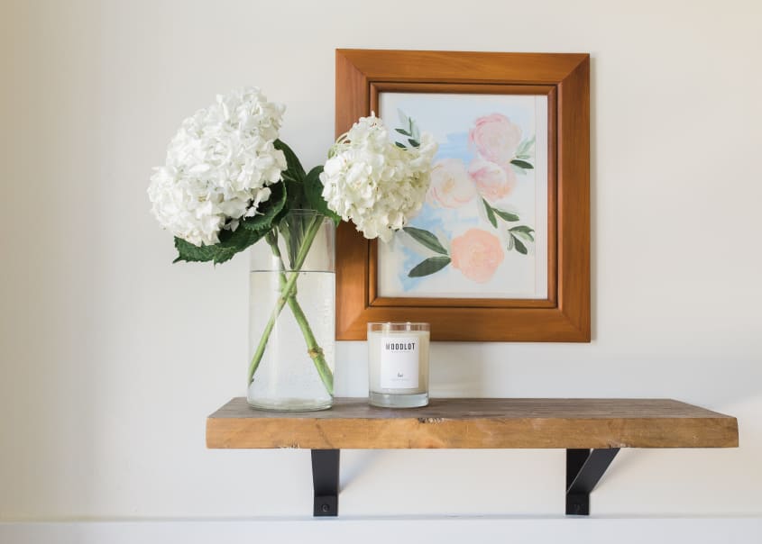 A candle and flower vase on a shelf