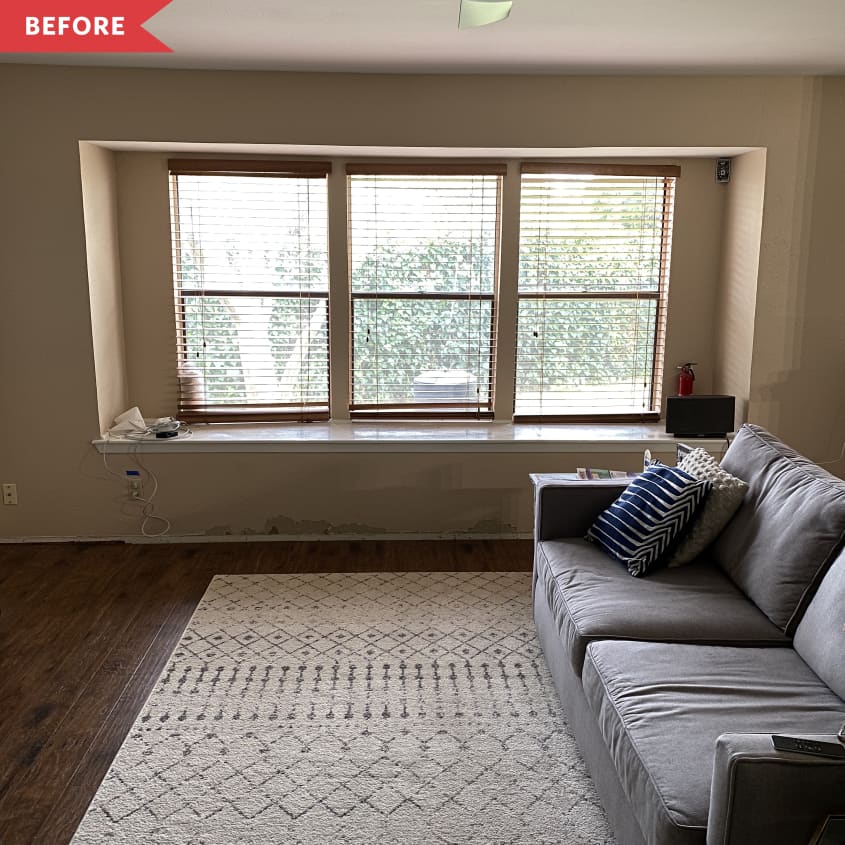 Gray couch in front of large window with cream-colored area rug