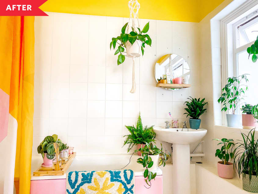 After: Bathroom with white tile, yellow walls, round mirror, and tons of plants