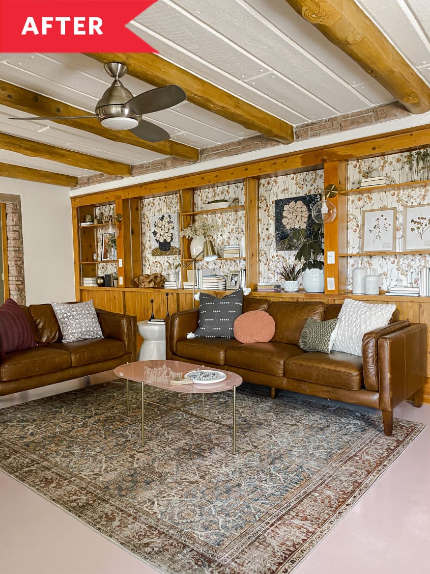After: Cozy living room with leather sofas, floral wallpaper behind wooden wall-to-wall bookshelves, and wooden beams across ceiling