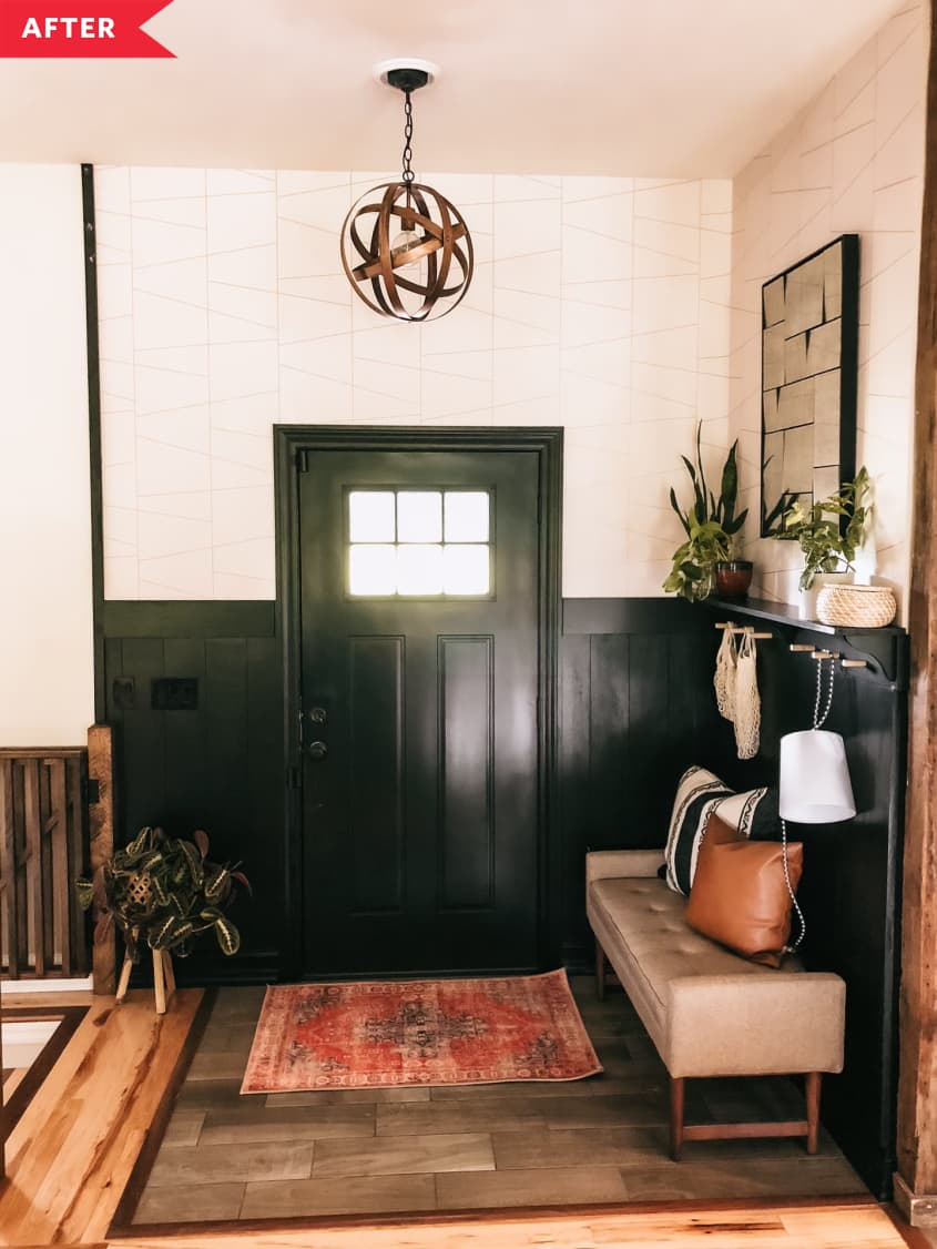 After: Entryway with black wood paneling, black door, and globe pendant light