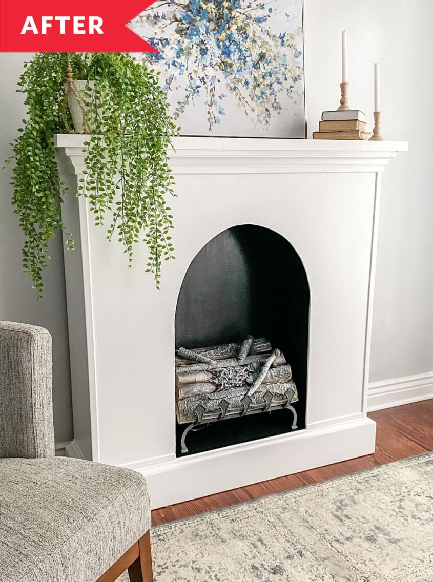 Faux white fireplace with candles, plant, and artwork on mantel