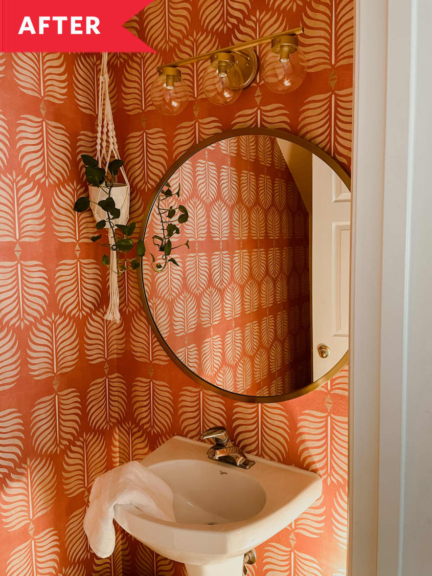 Bathroom with round mirror above sink and orange boho wallpaper