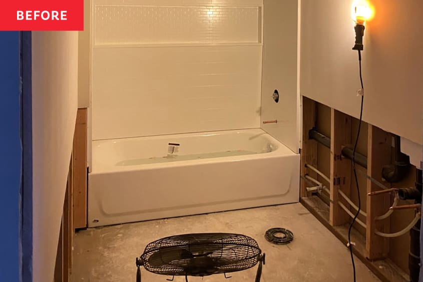 A bathroom in construction with drywall being put up, a bare wall, and a shower in the far wall's alcove.