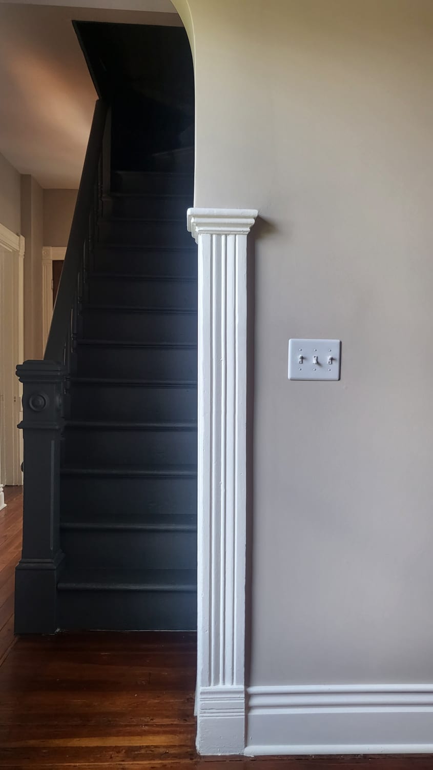 View of stairs that shows a beige-painted wall with a white light switch plate