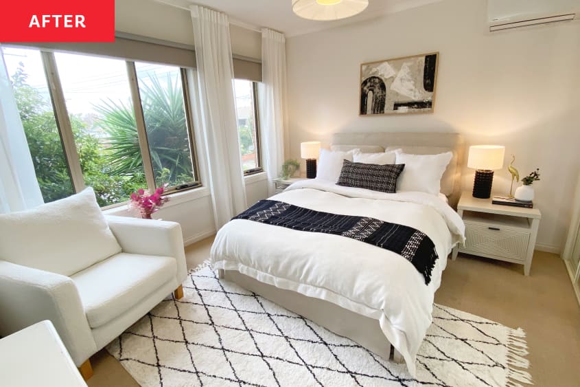 White bedroom after renovation with neutral colored textile headboard and plush graphic rug.