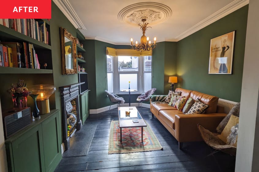 Living room after renovation. Green walls, wood floor, colorful area rug, gold/ochre leather sofa, wood and glass coffee table, black ornate fireplace