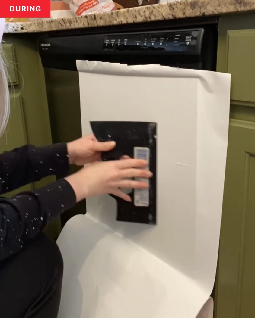 During: adding contact paper onto dishwasher with smoothing tool